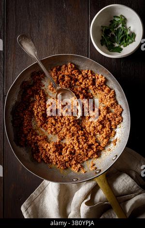 ragù alla bolognese: Salsa di pomodoro, carne di macina, cipolla e carote, servita in padella su tavola di legno. Vista dall'alto. Foto Stock