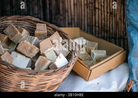 Un cesto rustico pieno di un assortimento di saponi tradizionali, ognuno con ingredienti naturali e una lavorazione artigianale senza tempo. Foto Stock