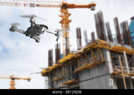 Drone con macchina fotografica che vola vicino a un edificio incompiuto. Veicolo aereo senza equipaggio per la sorveglianza Foto Stock