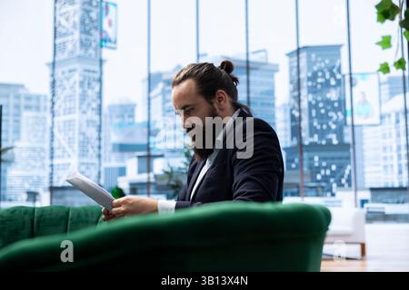 Il giovane direttore aziendale esamina le tendenze di vendita e i rapporti sul budget nel suo ufficio intelligente, garantendo redditività e successo aziendale attraverso processi decisionali e una pianificazione strategica efficaci. Foto Stock