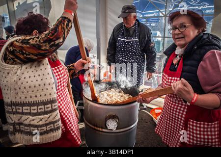 RITORNO PETROVAC, SERBIA - 15 FEBBRAIO 2025: Donne che cucinano cvarci (cracklings di maiale) in un mercato a Backi Petrovac. I Cvarci, o cvarak, sono tipici maiali Foto Stock