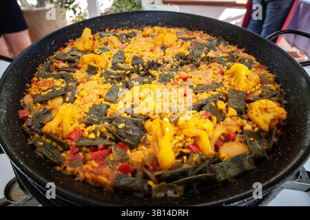 Paella vegana colorata di cavolfiore, peperoni, fagioli verdi e bollicine di riso allo zafferano in una paella, che offre un tocco senza carne sulla più grande varietà di Valencia Foto Stock
