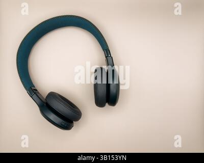 Grandi cuffie verdi con morbidi auricolari e fascia morbida si trovano sul lato sinistro dell'immagine su uno sfondo beige. Foto di alta qualità Foto Stock