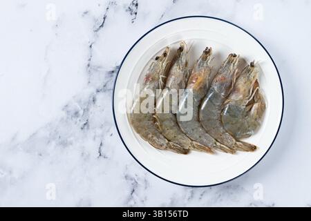 Gamberi crudi con i piedi bianchi freschi, gamberi tigre vannamei, su un piatto bianco Foto Stock