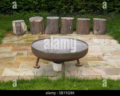 Area caminetto rustica all'aperto con posti a sedere in legno sul patio Foto Stock