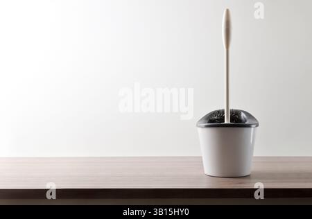 Pulizia del bagno con spazzolino con secchio su tavola di legno e sfondo bianco isolato. Vista frontale. Foto Stock