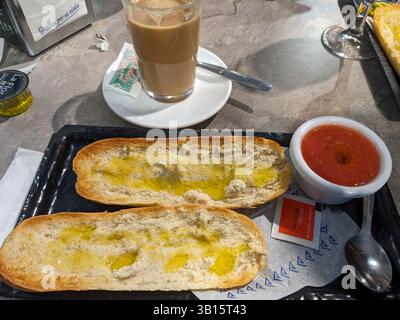 Una deliziosa colazione a buffet con pane tostato con olio d'oliva, pomodoro e una caffetteria con leche. Un inizio perfetto. Foto Stock