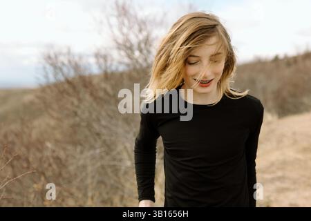 Un ragazzo che cammina con un sorriso in una giornata di primavera ventilata Foto Stock