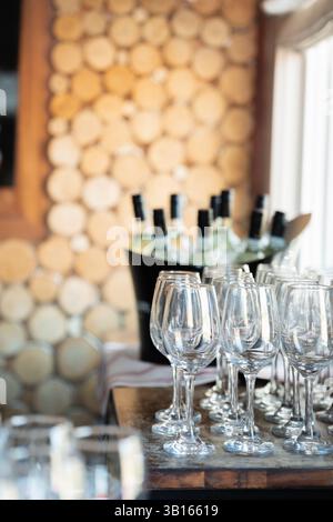 I bicchieri da vino vuoti accanto alle bottiglie ghiacciate su un bancone in legno rustico Foto Stock