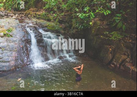 Una donna in una piscina alla base di una piccola cascata, Costa Rica, penisola di osa Foto Stock