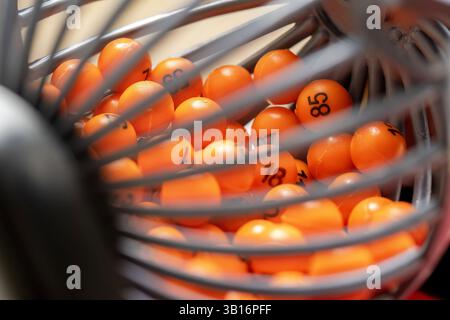 Primo piano estremo di palle della lotteria numerate arancioni all'interno di una gabbia rotante, concetto di casualità, gioco di bingo, gioco d'azzardo, sistema di estrazione o meccanismo della lotteria Foto Stock