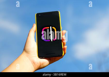 Persona che tiene in mano uno smartphone con l'app Instagram aperta, circondata da elementi di editing video. creazione, modifiche e contenuti digitali a tema blu Foto Stock