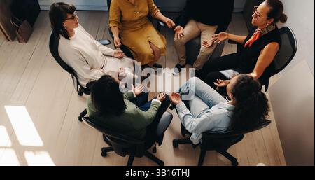 Un gruppo di uffici diversificato si impegna in esercizi di consapevolezza, promuovendo la salute mentale e l'unità di squadra sul posto di lavoro. Foto Stock