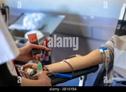 Il medico preleva sangue dal braccio del donatore femminile usando l'ago in clinica Foto Stock