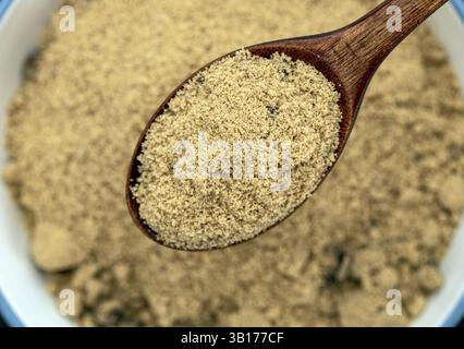 Cucchiaio per zucchero di canna biologico: Vista ravvicinata di un cucchiaio di legno che contiene un cucchiaio di zucchero di canna biologico, con una quantità maggiore dello stesso zucchero nel Foto Stock