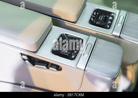 vista dettagliata dei comandi premium del sedile e della console all'interno di un'auto elettrica moderna, evidenziandone le caratteristiche avanzate di comfort e il design raffinato. Foto Stock