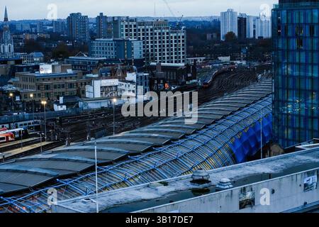 Il crepuscolo si adagia sul paesaggio urbano di Londra, con binari e piattaforme che si intrecciano tra edifici e infrastrutture vicino alla stazione Waterloo Green. Foto Stock