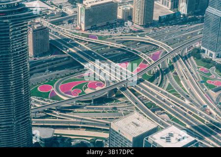 Vista rialzata di uno svincolo autostradale con aiuole paesaggistiche a Dubai, Emirati Arabi Uniti, che mostra la pianificazione urbana e le infrastrutture di trasporto Foto Stock