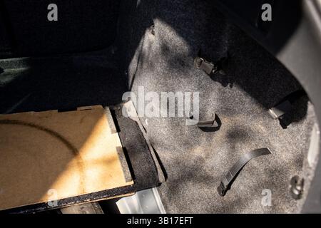 Il bagagliaio della vettura e lo spazio per la ruota di scorta sono polverosi e sporchi. Foto Stock