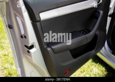 Portiera dell'auto dopo la pulizia, sia la plastica che la pelle brillano. Foto Stock
