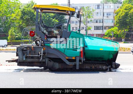 Macchina per asfalto che lavora per la posa di nuovo asfalto su strada. Foto Stock