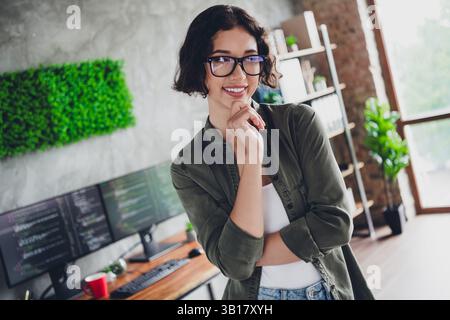 Giovane programmatrice donna in uno spazio di lavoro informale focalizzata sul lavoro con i computer in ufficio, che presenta una programmazione e un design moderni Foto Stock