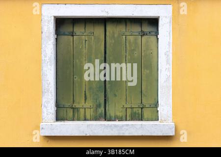 Vecchie persiane verdi sul muro giallo Foto Stock