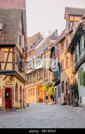 Strada pittoresca a Riquewihr, Alsazia, Francia, caratterizzata da case colorate e in legno e sentieri acciottolati in un villaggio medievale ben conservato. Foto Stock