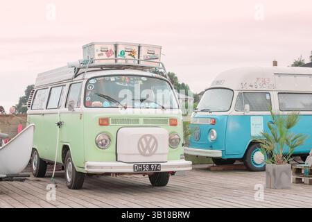 2 camper vintage Volkswagen California parcheggiato vicino a una costa panoramica, che evoca la libertà, i viaggi estivi e la cultura del surf. Foto Stock