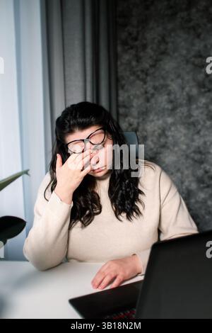 Donna caucasica stanca che si sente stressata da problemi di lavoro. Bruciatura da irritazione. Sfregamento degli occhi. Gestione delle scadenze di lavoro. Non dormi abbastanza. Foto Stock