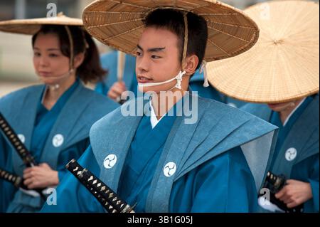 Uomo e donna vestiti con un abbigliamento formale da samurai con cappello di paglia che regge una spada katana durante il Festival del Castello di Hikone a Shiga, in Giappone. Foto Stock