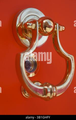 La porta bussa su una vivace parete rossa ad un'affascinante entrata Foto Stock