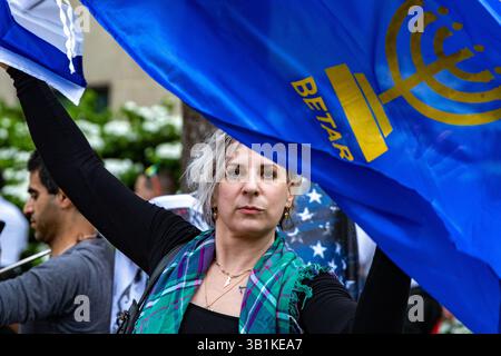 Washington, District of Columbia, USA. 25 aprile 2025. Un contromanifestante pro-israeliano detiene una bandiera per Betar, un controverso movimento sionista revisionista di destra che è stato inserito nella lista nera dalla Lega anti-diffamazione, durante una manifestazione contro il coinvolgimento degli Stati Uniti nel genocidio in corso dei palestinesi a Gaza. Crediti: Tom Hudson/ZUMA Press Wire/ZUMA Wire/Alamy Live News Foto Stock