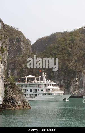 Barca che emerge da dietro una scogliera a LAN ha Bay, Vietnam. Foto Stock