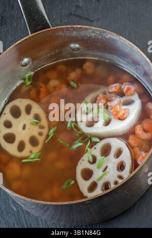 Zuppa di gamberi asiatici in una casseruola di rame con radici di loto Foto Stock