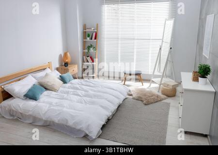 Letto comodo, comò e specchio in camera da letto Foto Stock