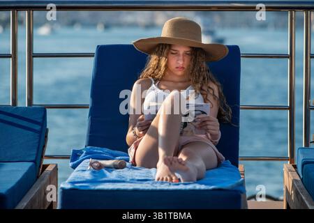 Ragazza turistica che legge un libro all'interno della crociera Harmony V Classical Greece nel Mediterraneo. La crociera Harmony V classica in Grecia lo esplora Foto Stock