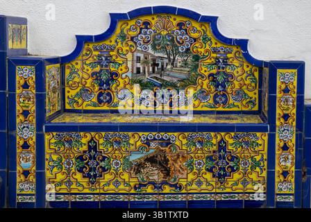 Panca su una strada, decorata con tradizionali piastrelle di ceramica. Parete bianca sullo sfondo. Firgas, Las Palmas, Gran Canaria, Isole Canarie, Spagna. Foto Stock