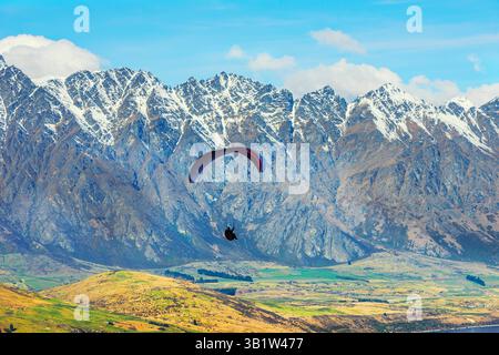Parapendio vicino alla catena montuosa Remarkables innevata, Queenstown, South Island, nuova Zelanda Foto Stock