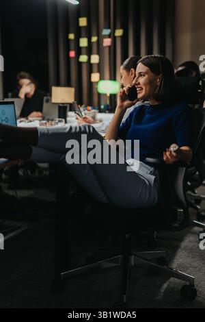 Un team dedicato collabora in un ufficio, concentrandosi sulle proprie attività fino a tarda sera. Foto Stock