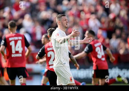 Leverkusen, Germania. 26 aprile 2025. Frustrato da Jeffrey Gouweleeuw (A), in background il Team Leverkusen festeggia. Bundesliga, Matchday 31, Bayer 04 Leverkusen (LEV) vs. FC Augsburg (A), il 26 aprile 2025, a Leverkusen, Germania. #Le normative DFL vietano qualsiasi uso di fotografie come sequenze di immagini e/o quasi-video # credito: dpa/Alamy Live News Foto Stock