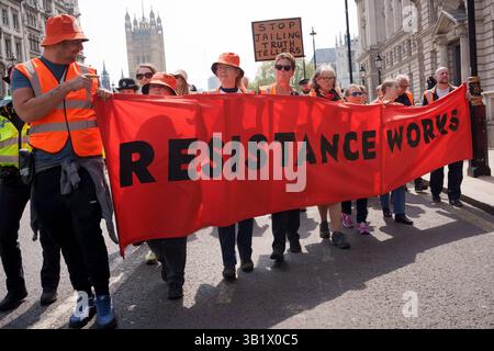 Gli attivisti del gruppo "Just Stop Oil anti-fossile Fossil FUEL FUEL FUEL" marciano lungo Whitehall per il loro ultimo evento, che segnò la fine della loro serie di 3 anni di proteste contro il cambiamento climatico, il 26 aprile 2025 a Londra, Inghilterra. La richiesta iniziale di Just Stop Oil di porre fine a nuovi progetti di esplorazione di petrolio e gas durante i successivi governi conservatori è ora la politica del governo laburista. Durante i loro 3 anni di storia di azione diretta (quando in genere, la vernice arancione veniva spruzzata su showroom e banche di automobili, zuppa gettata su dipinti di gallerie d'arte e occupazioni di cavalletti autostradali nelle ore di punta), sostenitori Foto Stock