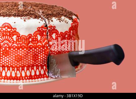 torta fatta in casa con panna e pizzo rosso decorata con gocce di cioccolato. Foto Stock