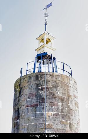 Un'inquadratura ad angolo basso mostra la parte superiore di una torre di pietra, probabilmente un faro o una struttura simile. La torre è costruita in pietra intemprata Foto Stock