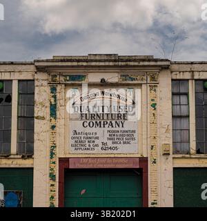 Edificio abbandonato Banana Warehouse a York, precedentemente sede di un negozio di mobili usati, con vernice incrinata, finestre rotte e cartellonistica sbiadita su una nuvolosa Foto Stock