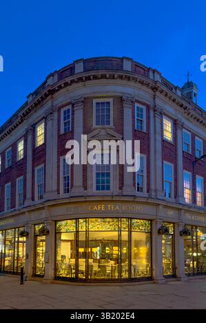 Vista curva d'angolo delle sale da tè del Betty's Café a York al tramonto, interni illuminati e visibili attraverso finestre in stile Art Deco. REGNO UNITO Foto Stock