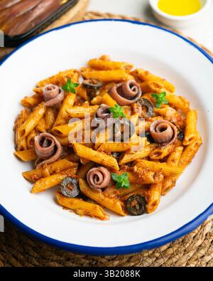 Pasta italiana maccheroni penne alla siciliana con acciughe e pomodoro Foto Stock