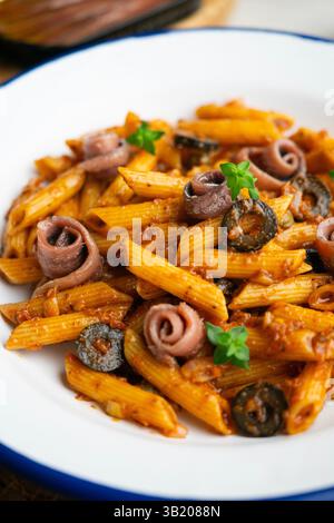 Pasta italiana maccheroni penne alla siciliana con acciughe e pomodoro Foto Stock