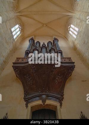 Vista ad angolo basso del grande organo in legno situato in una chiesa gotica pianeggiante e ben illuminata nel sud-ovest della Francia senza persone Foto Stock