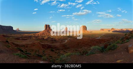 Vista panoramica delle iconiche arenarie della Monument Valley illuminate dalla calda luce del tramonto, situate sul confine tra Arizona e Utah, Stati Uniti Foto Stock